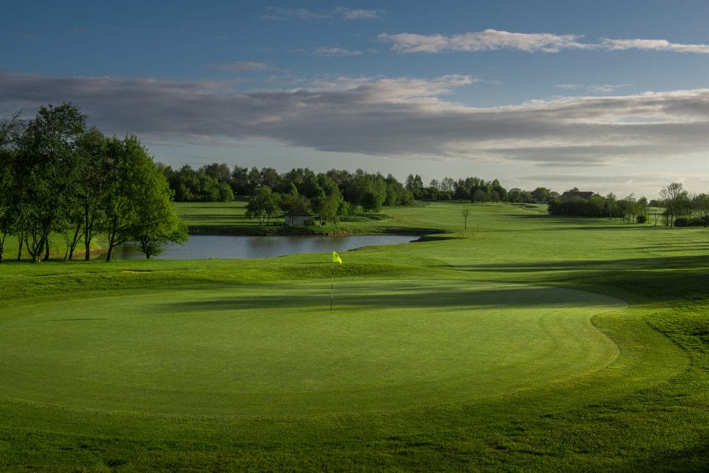 sunlight soaking 18 hole golf course in bristol with water splitting the fairway