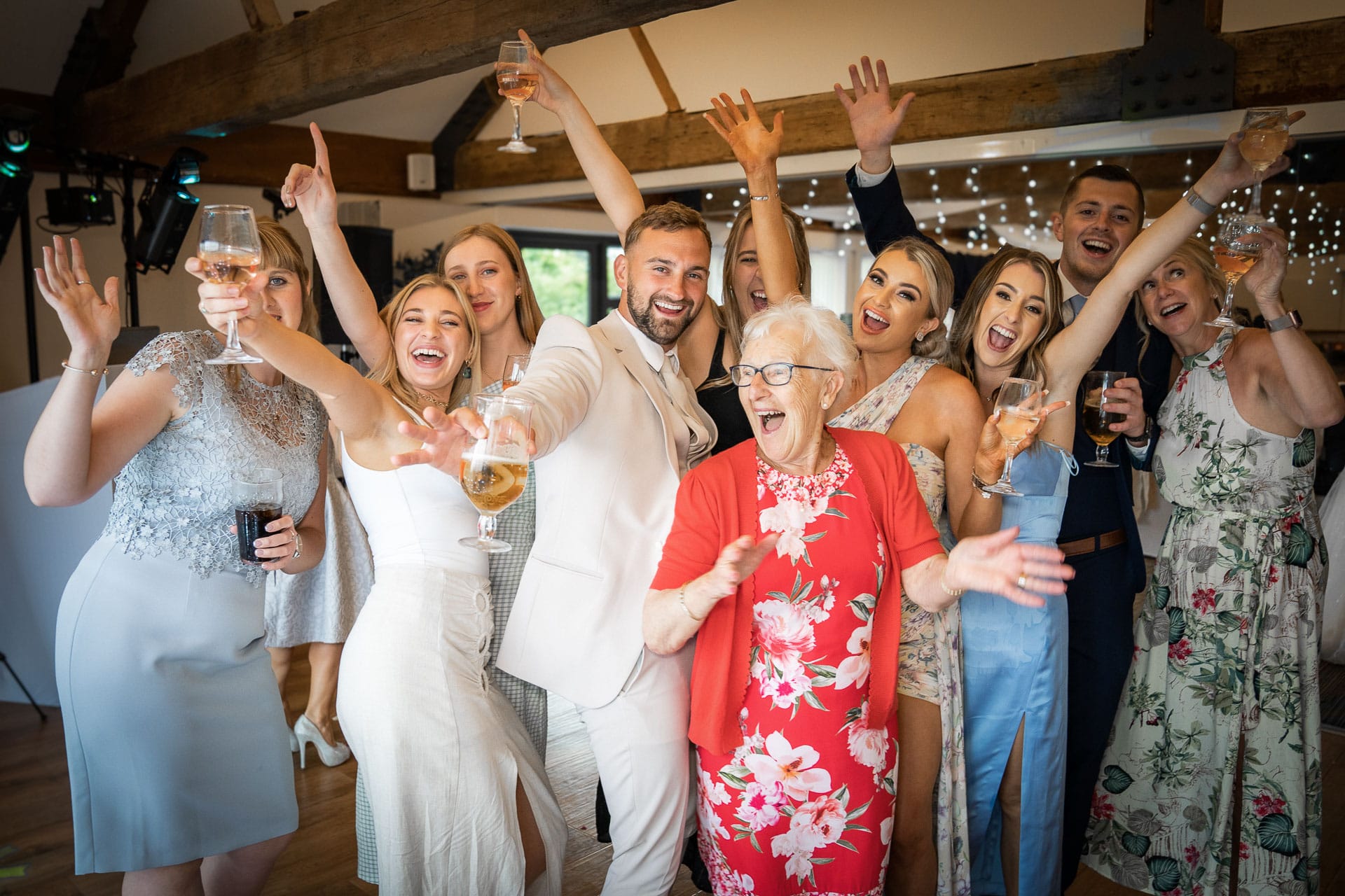 family members laughing and dancing holding drinks at a wedding venue near bristol