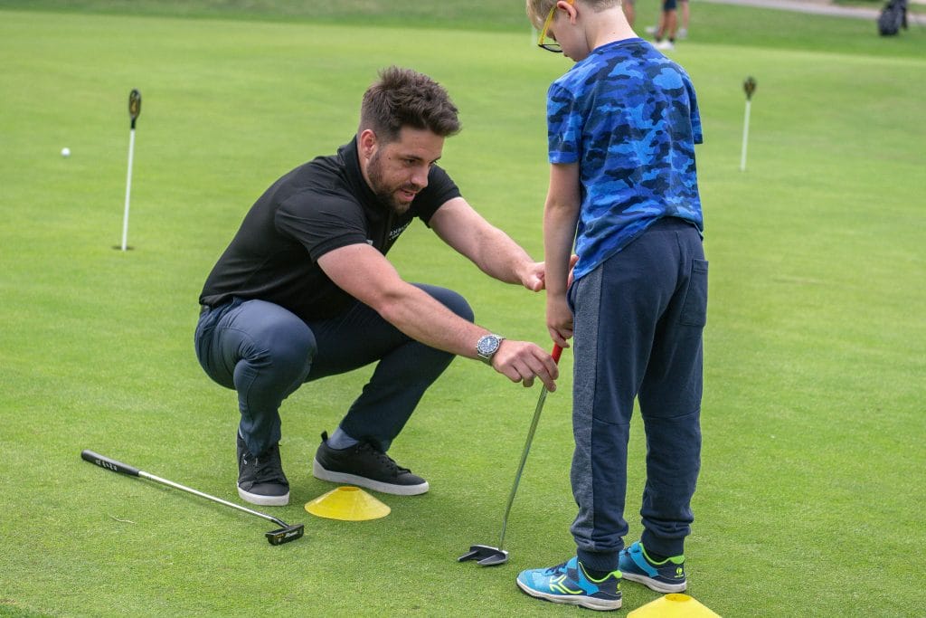 golf proffesional in bristol teaching young boy how to putt