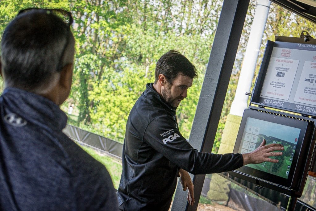 pga golf coach talking through on-screen stats during golf lesson in bristol