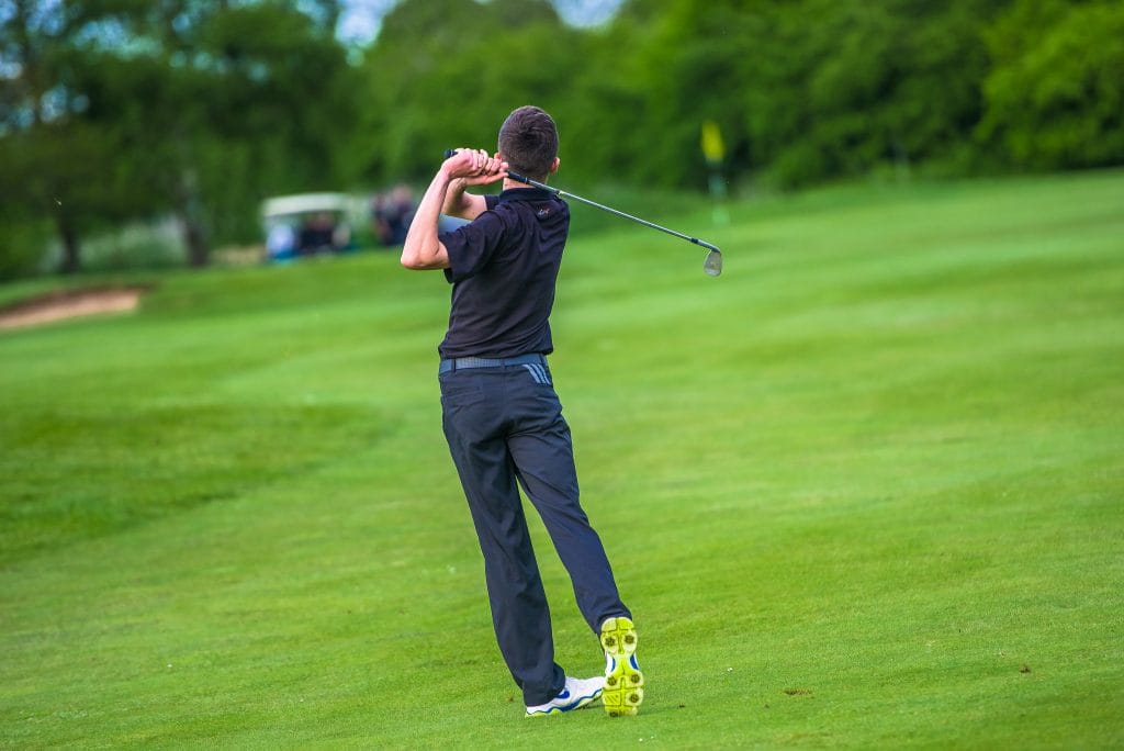 Young man hitting a golf shot towards the green at a golf course in Bristol.