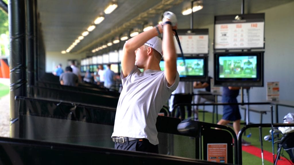young man hitting ball out of trackman driving range in bristol