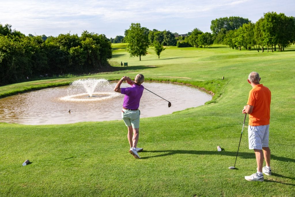 two man playing golf in bristol with a hole over a water fountain