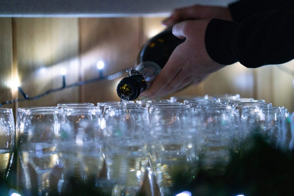 dozens of champagne glasses being filled in preparation for an xmas party in bristol