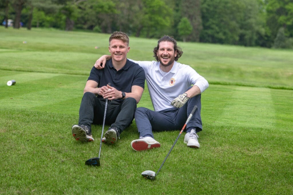 two guys sat on golf course smiling with a golf membership in bristol